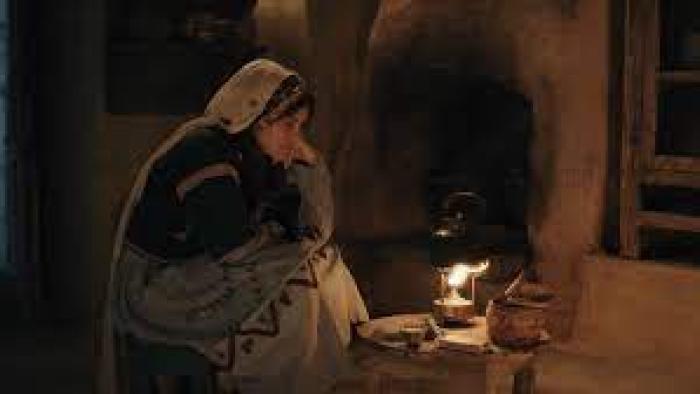Farha: A girl sits in a dark cave lighted by kerosene lamp