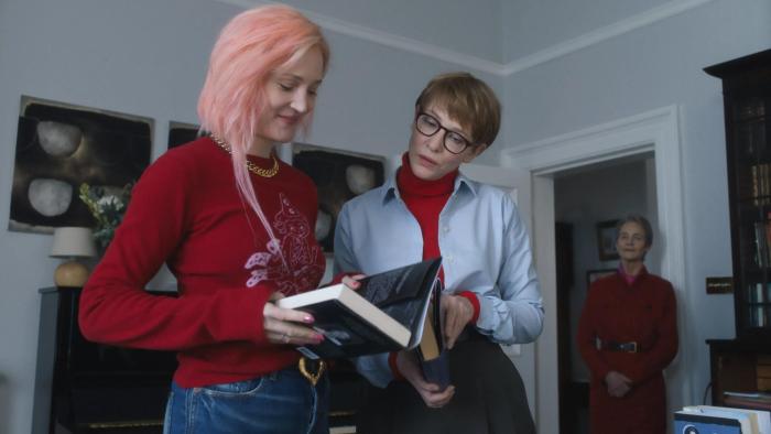 Father Mother Sister Brother movie: Two women look at books together in a modern apartment while their mother watches from the background