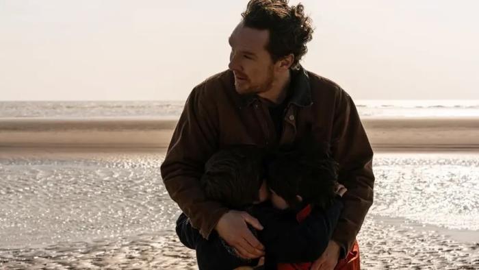 The Thing with Feathers: Benedict Cumberbatch leans down to hug his character’s two sons on the beach, with the sea behind them