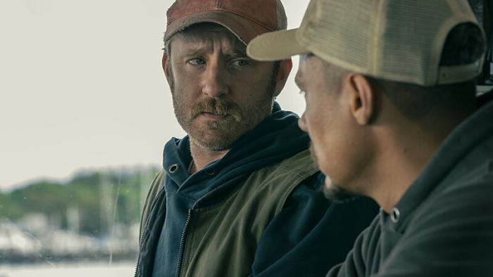 Finestkind Movie: Two men wearing baseball caps speak on a boat in a bay