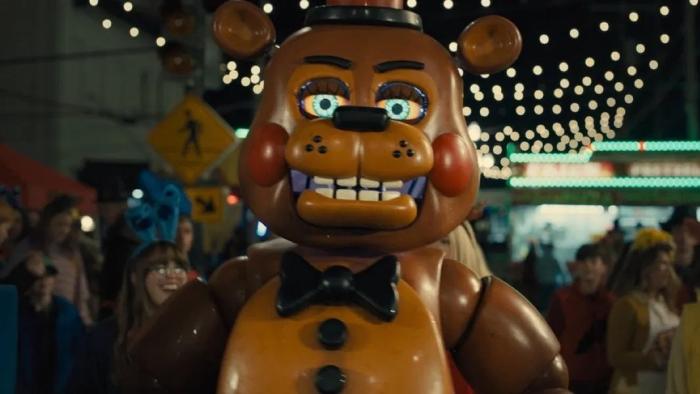 Five Nights at Freddy's 2 Movie: A large animatronic bear wears a bow tie and top hat in brightly lit arcade