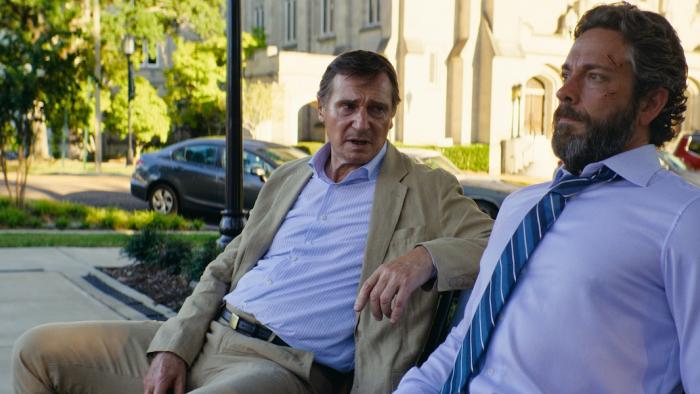The Fix Movie: Dressed for business, Larry speaks to an angry-looking Tucker on a park bench