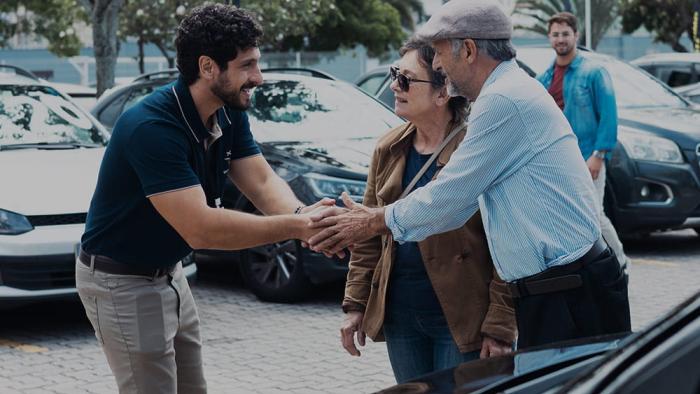 Flywheel: Ignition of the Soul: Mario Bergeira shakes hands with a man at a used car dealership