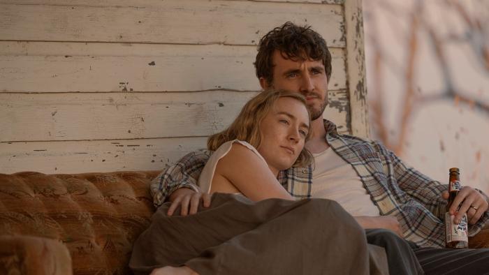 Foe: Saoirse Ronan and Paul Mescal as married couple Hen and Junior, sit on a bench, Hen leaning on Junior holding a beer.
