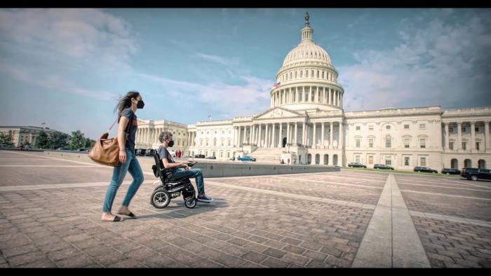 For Love & Life: No Ordinary Campaign movie: white woman pushes white man in wheelchair across front of U.S. Capitol building