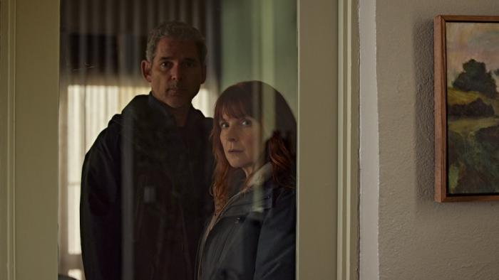 Force of Nature: The Dry 2 Movie: Falk and his partner, Carmen, look suspiciously through a window