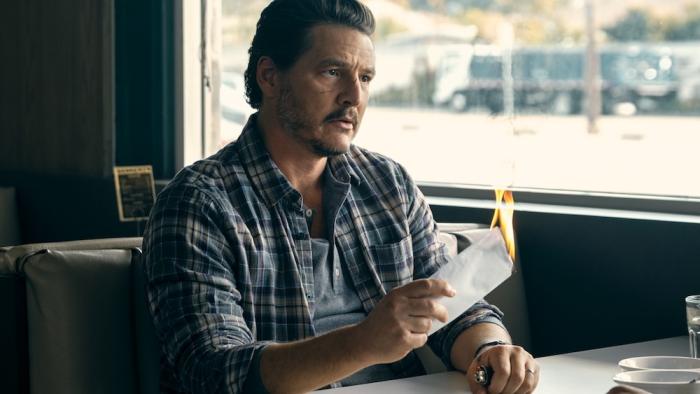 Freaky Tales Movie: In a diner booth, Clint (Pedro Pascal) holds a flaming envelope