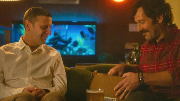 Friendship movie: Craig and Austin sit together looking into a cardboard box; a fish tank is behind Craig
