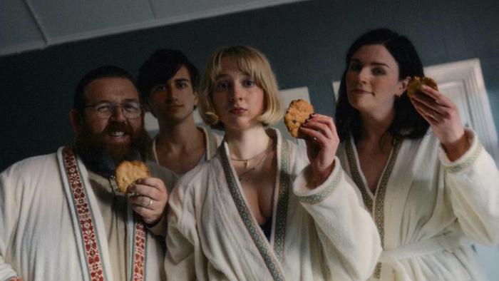 Get Away: Nick Frost, Sebastian Croft, Maisie Ayres, and Aisling Bea stand in white dressing gowns holding up cookies