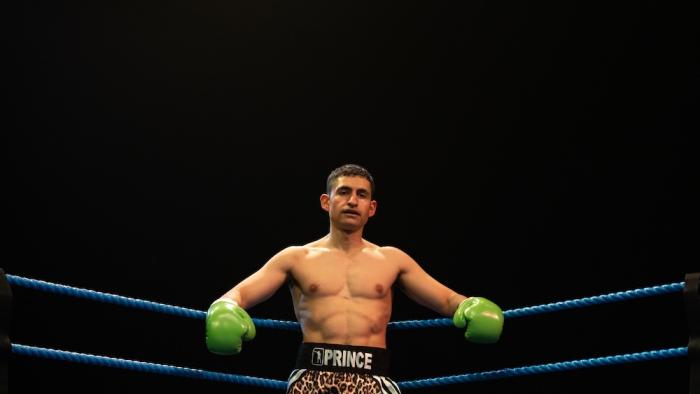 Giant: Boxer with green gloves in a ring, wearing leopard-print shorts, under spotlight