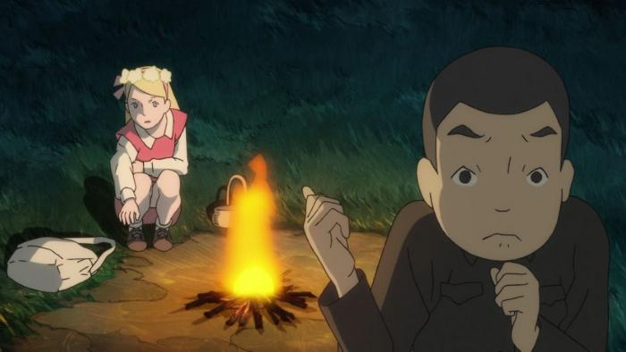 Giovannis Island movie: Junpei and Tanya are around a campfire at night, Tanya is sitting reaching for her book bag, while Junpei is standing looking nervous and grasping his chin.