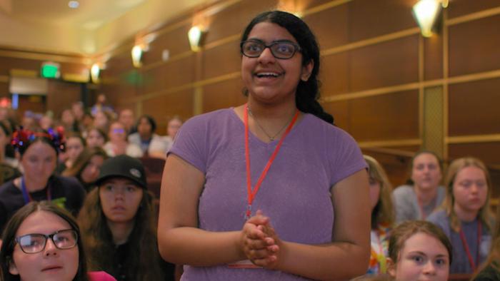 Girls State: Nisha Murali claps while standing in an audience
