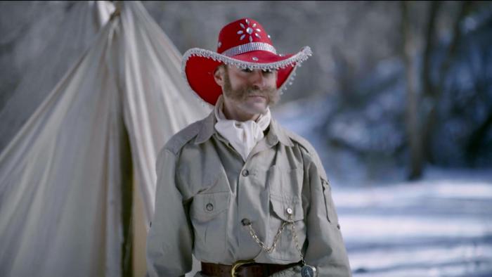 Go West Movie: A man wearing a khaki bush jacket, an ascot, and a red cowboy hat
