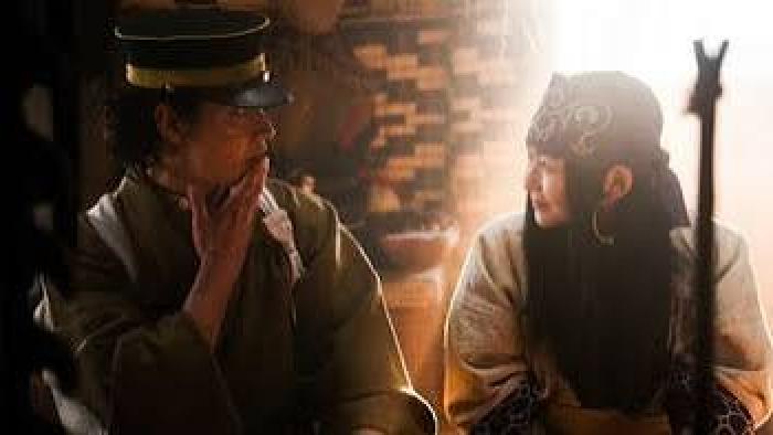 Golden Kamuy: Two people in historical attire sharing an intense gaze, soft focus background.
