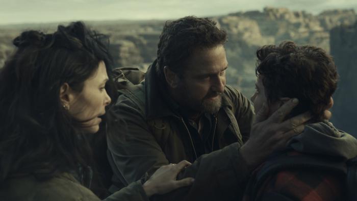 Greenland 2: Migration Movie: On top of high cliffs, John holds Nathan's face in his hands, as if encouraging him