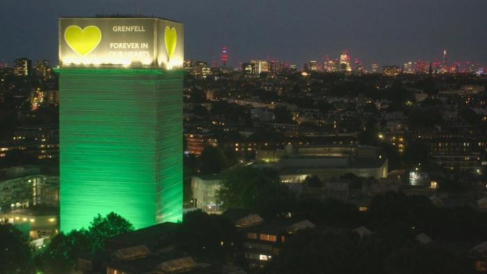 Grenfell—Uncovered: Grenfell Tower is lit up in yellow and green with "Grenfell forever in our hearts" written on the top