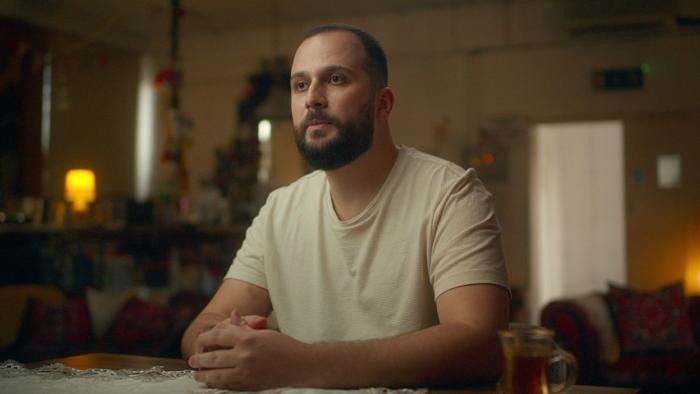 Grenfell—Uncovered: A former resident sits at a table with his hands clasped as he recalls his experience of the Grenfell Tower fire