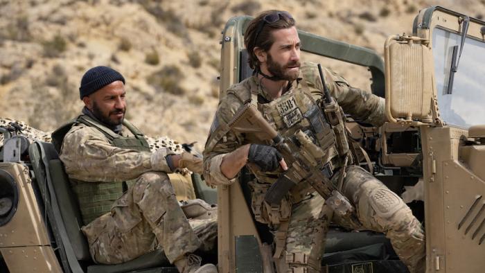 Guy Ritchie's The Covenant Movie: Ahmed (Dar Salim) sits in the back of an Army Jeep, while Sergeant John Kinley (Jake Gyllenhaal) begins to climb out