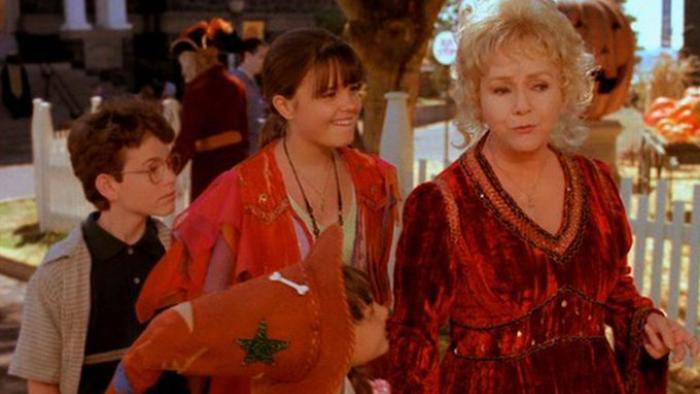 Halloweentown Movie: Grandma and two kids walk through Halloween-themed outdoor area