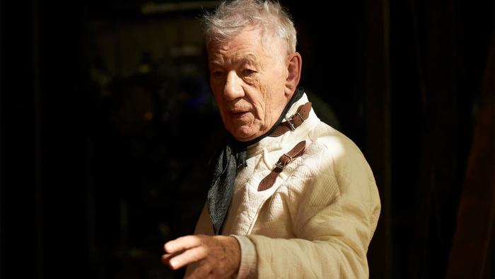 Hamlet: Ian McKellen reaches out an arm as he speaks, his white fencing gear illuminated against a black background