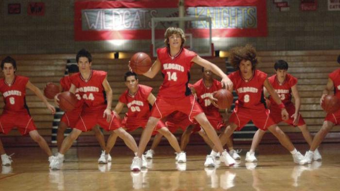 High School Musical Movie: Troy bounces a basketball in front of teammates who are in musical formation