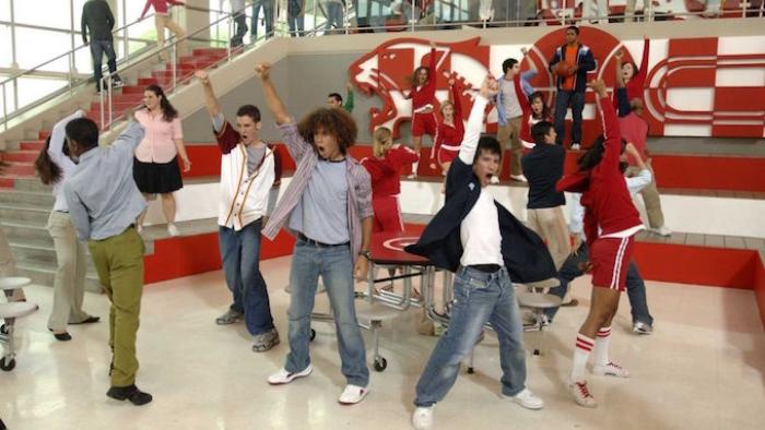 High School Musical Movie: Musical number with high school students throwing their fists up into the air at school