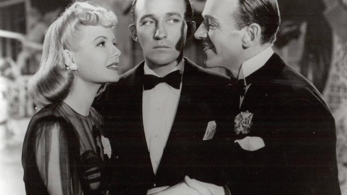 Holiday Inn Movie: Two White men and a blonde White woman talk, dressed in formalwear