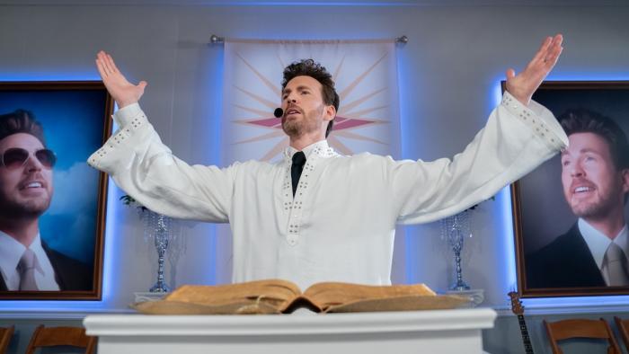 Honey Don't! Movie: Reverend Drew Devlin (Chris Evans) preaches from a pulpit, framed photos of himself on the wall