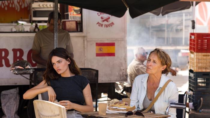 Hot Milk: A young White woman and her wheelchair-bound mother sit at a table outside a churro truck