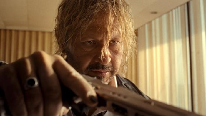 Hot Spot movie: A man with long hair points a gun indoors