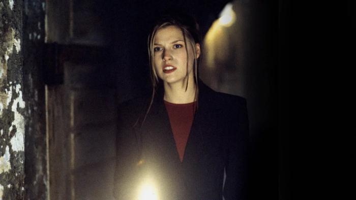House on Haunted Hill: Melissa holds a flashlight in a dark room with disheveled hair, looking tense.