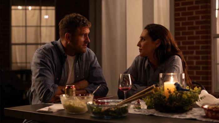 How Hard Can It Be movie: Jack Kesy and Anna Schafer look at each other at the dinner table outside at night