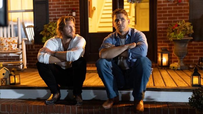 How Hard Can It Be movie: Jack Kesy and Matt Barr sit on the steps of a house outside, talking