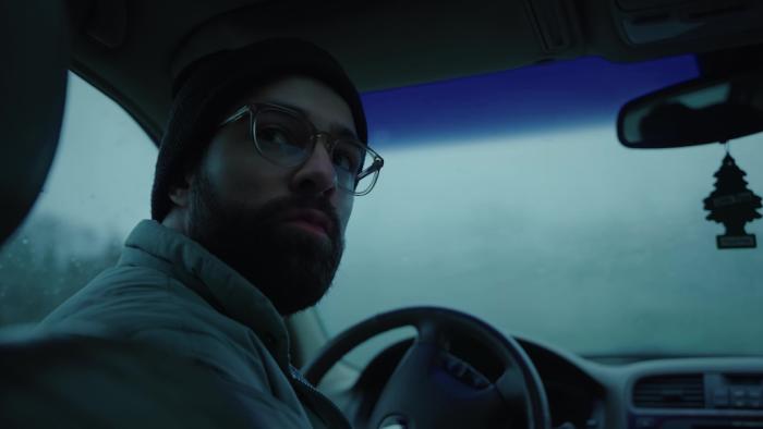 Hunting Matthew Nichols Movie: Markian is in the driver's seat of his car, head turned around to look at the rear