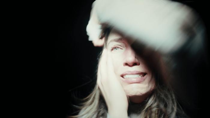 Hunting Matthew Nichols Movie: In the dark, Tara appears terrified, an arm over her forehead, a light shining in her face