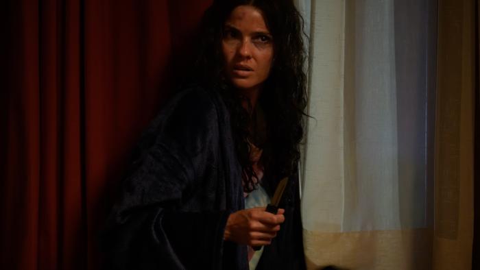 Hunting Season Movie: Wounded and scared, January (Shelley Hennig) crouches near a wall while holding a small knife