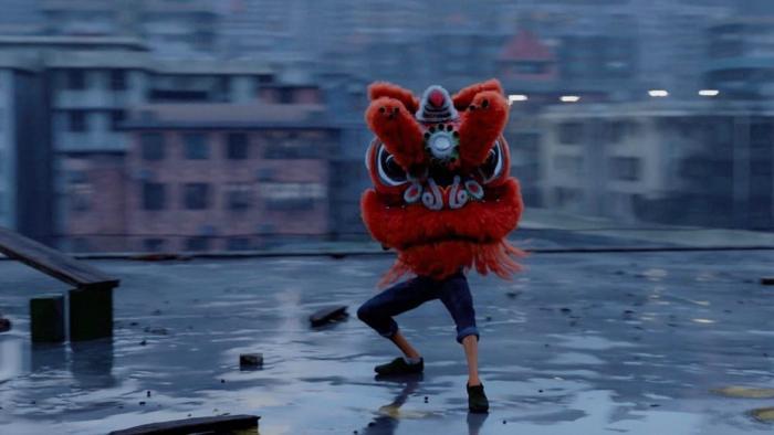 I Am What I Am: A Juan dances on a rooftop with his red lion dancer fheaddress