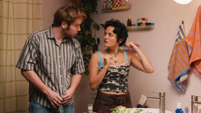 I Want Your Sex movie: Cooper Hoffman stands at the bathroom sink while talking to Chase Sui Wonders, who's brushing her hair