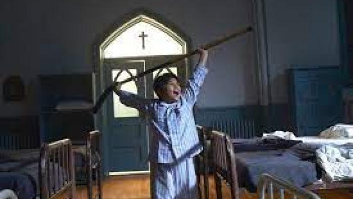 Indian Horse: Boy in pajamas holds hockey stick