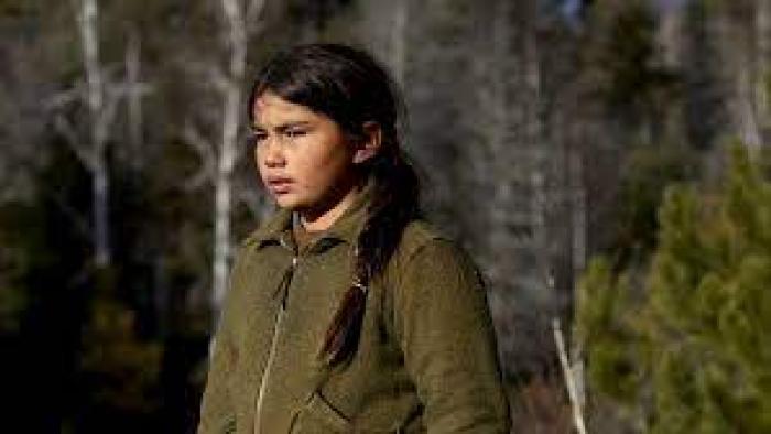 Indian Horse:  Indigenous child stands in the woods looking pensive