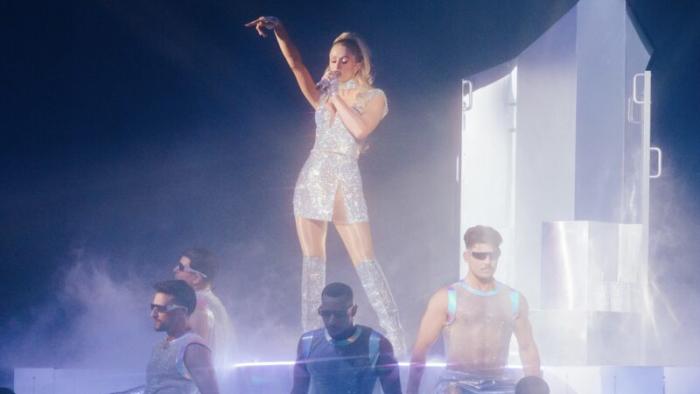 Infinite Icon: A Visual Memoir movie: Hazy image of Paris Hilton singing in a big stage production with shirtless male dancers