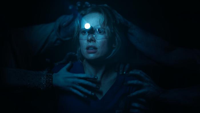 Insidious: Out of the Further Movie: Gemma, wearing dental goggles, is clutched at by several ghostly hands in the Further