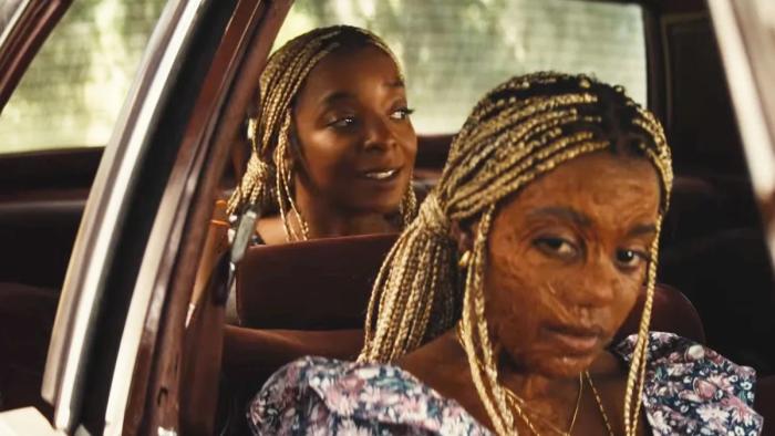 Is God Is movie: A Black woman with burn scars on her face sits in the front seat of a car, her sister in the back seat