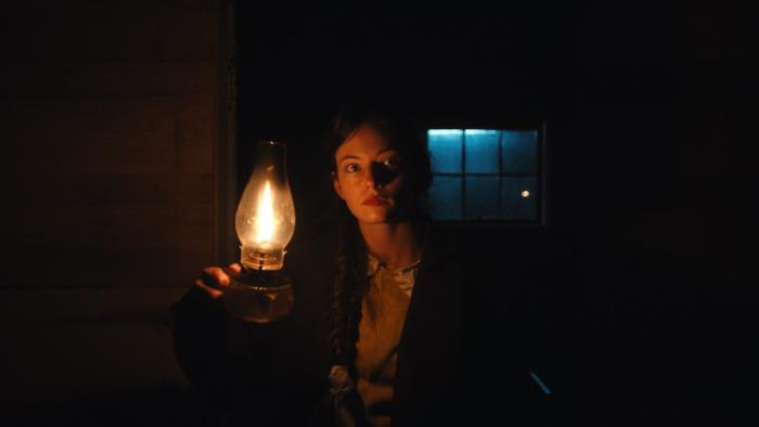The Isolate Thief Movie: Ada searches the outpost at night, holding a kerosene lamp up to pierce the darkness