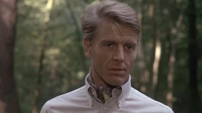 The Day of the Jackal: Edward Fox stands in a forest wearing a light-coloured shirt