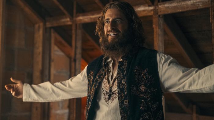 Jesus Revolution Movie: Jonathan Roumie appear, looking like Jesus with his arms outstretched to his sides 