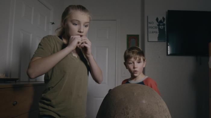 brother and sister looking at giant egg
