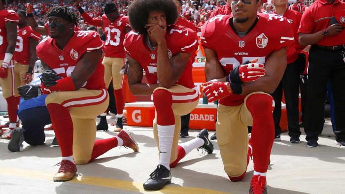 Colin Kaepernick (center) and San Francisco 49ers teammates taking a knee during the U.S. national anthem.