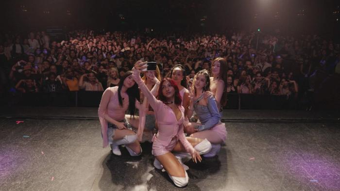 Katseye—Wild Hearts: The band KATSEYE posing on stage for a selfie with a cheering crowd behind them