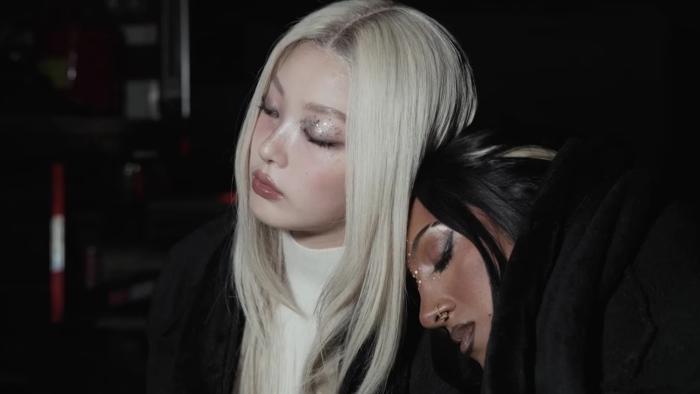 Katseye—Wild Hearts: KATSEYE members Lara Rajagopalan and Jeong Yoon-chae rest their heads together as they both look exhausted
